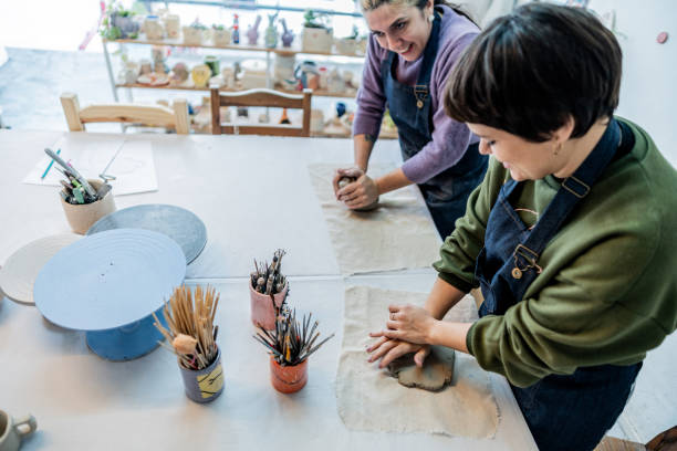 istock Potters friends modeling clay and talking at ceramics workshop 2162407641