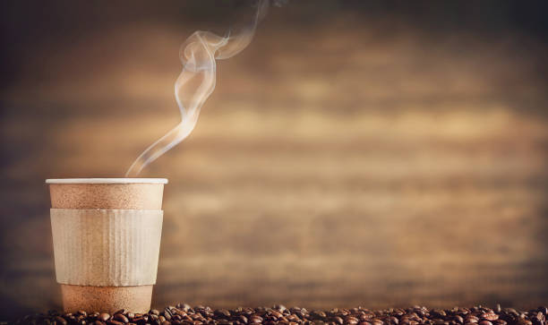 paper cup with hot smoke stands on coffee beans. copy space