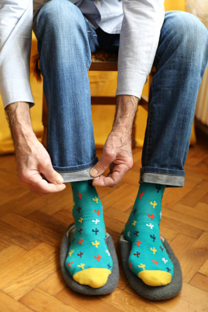 istock Close-up image of an elderly person putting on a colorful sock with cactus patterns. 2162414424