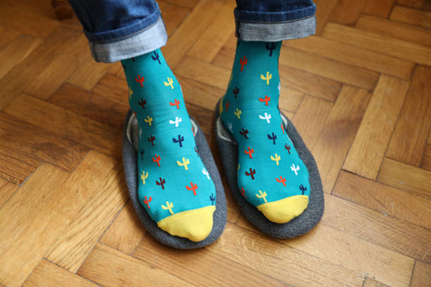 istock Close-up image of an elderly person putting on a colorful sock with cactus patterns. 2162414442