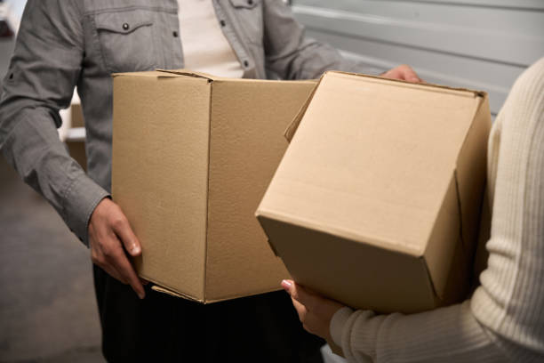 istock Man and lady carry boxes in storage unit 2162417402