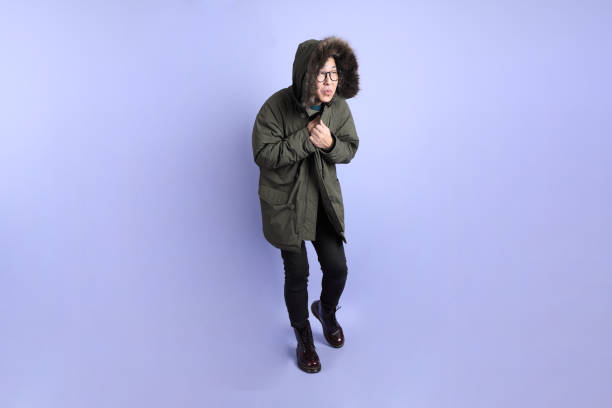 The Asian senior man wears winter clothes with gesture of  Feeling cold isolated on purple background.