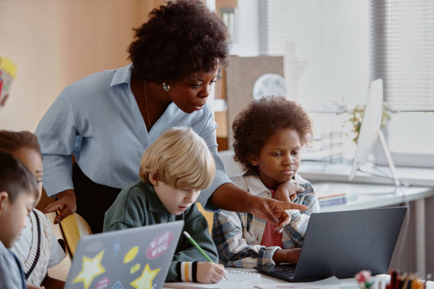 istock Female Teacher Helping Kids in Computer Class 2162419406
