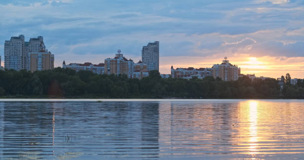 istock Sunset urban outskirts. Wide river, reflection sky water, sun's rays among clouds. High-rise residential buildings. Background 2162421573