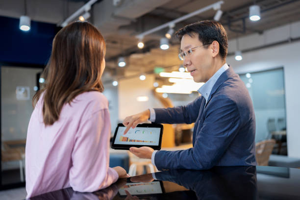 istock A financial advisor in a suit advises investors by showcasing graphical data on a computer to illustrate investment directions. The scene is set in a modern office, emphasizing the advisor's professional expertise and the clients' engagement strategies. 2162422494