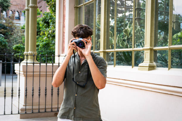 istock Young man taking a photo with an analog camera, in a nice place during a walk exploring the city 2162424367