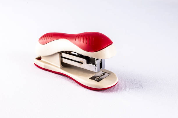 A red and white stapler sits on a white background