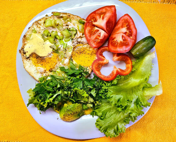 istock Fried two eggs and assorted fresh vegetables. Food on a blue plate. Yellow background 2162428291