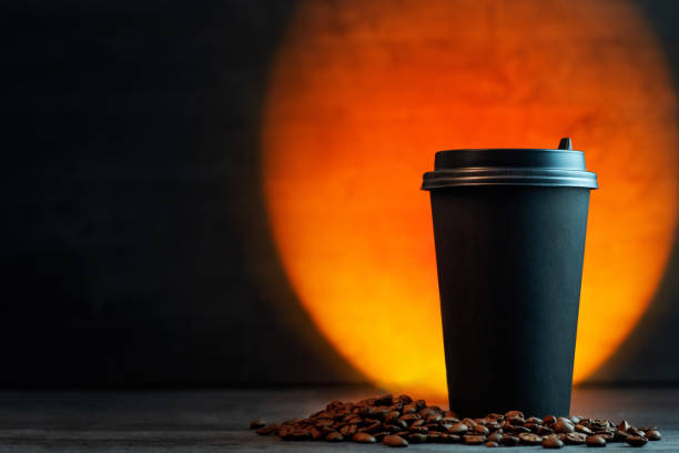 a paper cup of coffee on the table, colored backlight. Copy space