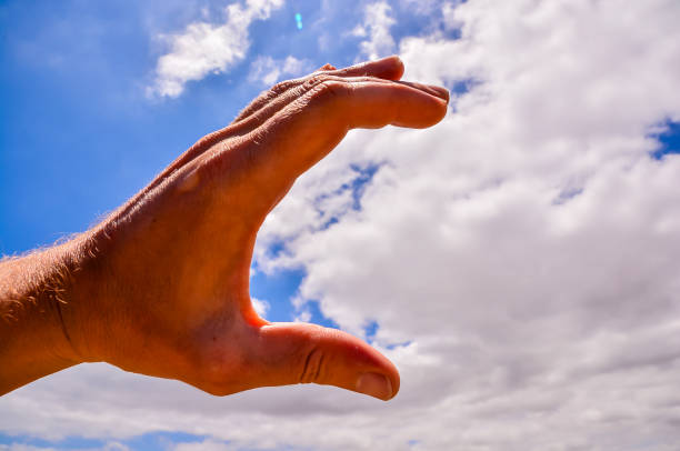 A hand is shown in the air with a cloud in the background. Concept of freedom and openness, as the hand is reaching out