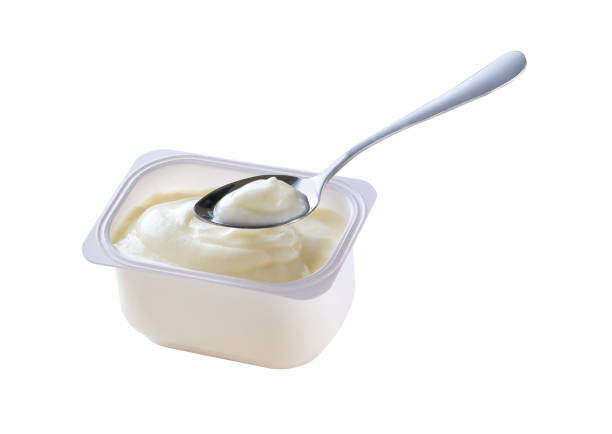 Open packing with yoghurt or tasty desser in a white plastic cup with a spoon isolated on a white background. Top view.