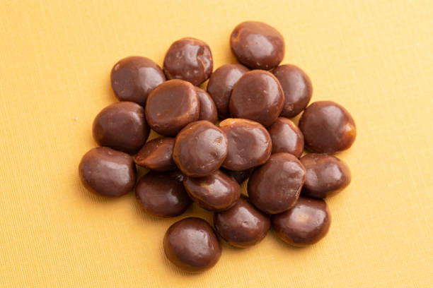 istock Chocolate Covered Caramel Disks on a Yellow Background 2162440200