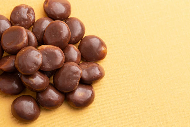 istock Chocolate Covered Caramel Disks on a Yellow Background 2162440202