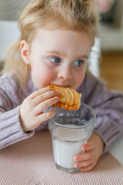istock Little cute girl drinks milk and eats cookies. 2162443439