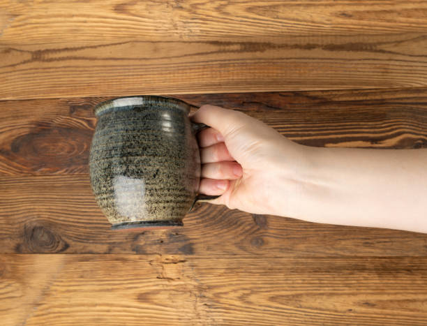 Hand Holds Cup, Empty Cup in Hands, Coffee Mug, Teacup Mockup, Cup in Arms on Wooden Table