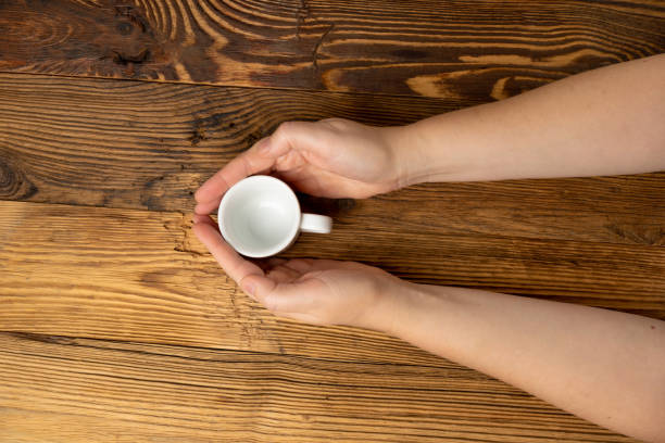 istock Hand Holds Cup, Empty White Cup in Hands, Coffee Mug, Teacup Mockup, Cup in Arms on Wooden Table 2162445809