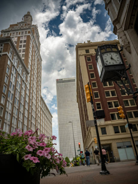 Petunia flowers with people walking on the sidewalk in downtown Tulsa Oklahoma with clock and buildings