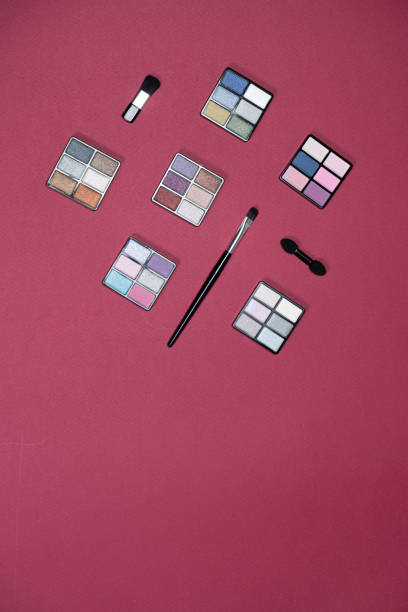 A set of multi-colored eyeshadow on a pink background, copy space for text.