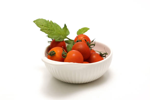 Cherry tomatoes in a white pottery bowl isolated on a white background.