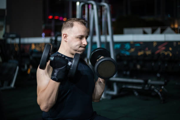 istock Man Lifting Dumbbells During Evening Workout at the Gym 2162450853