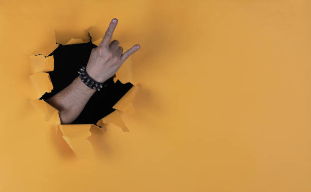istock rock musician hand in a paper hole 2162451019