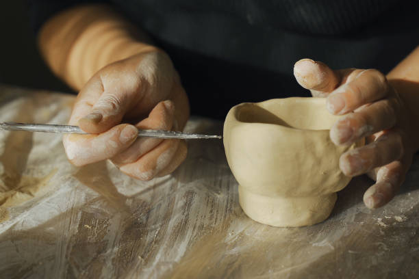 istock A woman makes holes using a tool in a clay craft - a candlestick. 2162451237