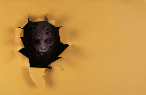 man in monster mask in yellow paper hole