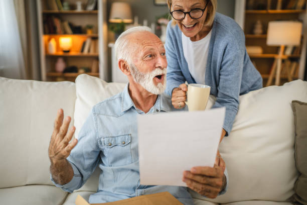 istock Senior couple read a letter document from envelope together at home 2162454212