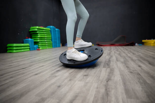 Woman Athlete Practicing Balance on a Blue Exercise Disc in a Gym