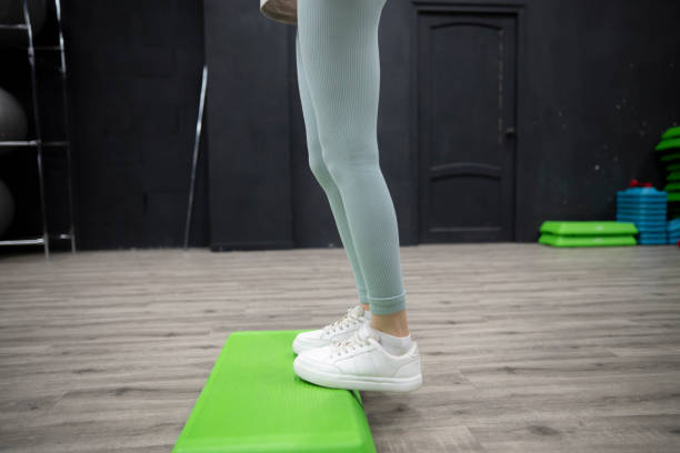 Female person Stepping Up On Green Aerobic Platform During Workout