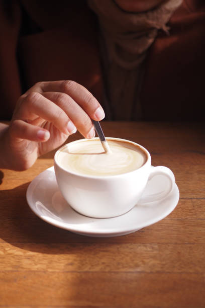 istock person hand stirring coffee with spoon. 2162471860