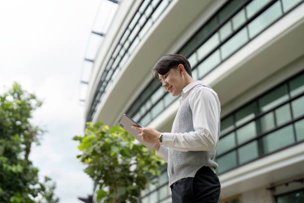 istock Young Professional Using Tablet Outside Modern Office Building on a Bright Day 2162473432
