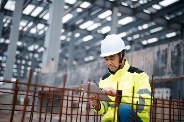 istock Middle-aged male construction technician wearing work helmet and protective workwear, working at a construction site 2162478860