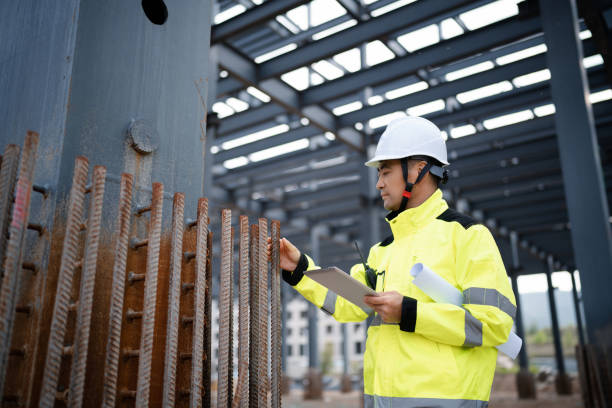 istock Middle-aged male construction technician wearing work helmet and protective workwear, working at a construction site 2162478883