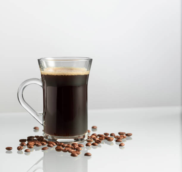 istock Mug of black coffee and coffee beans on a glass table. 2162480165