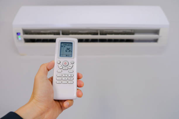 Man's hand using remote control open The air conditioner is cooled to 25 degrees Celsius in his bedroom. Health concepts and energy savings