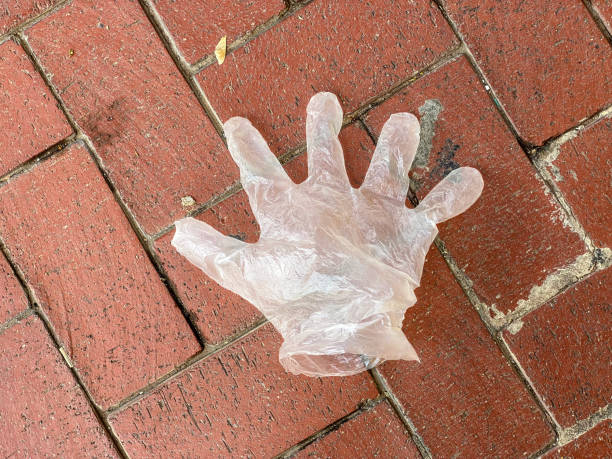 High angle close-up shot of a disposable plastic glove thrown over tiled floor