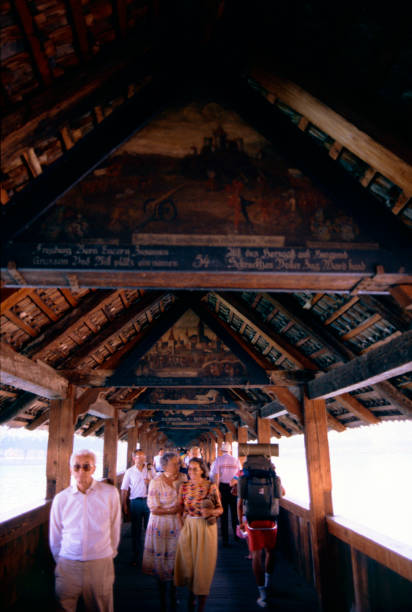Lucerne, Canton Lucerne, Switzerland, 3 August 1986: walking on the Chapel Bridge, the main tourist attraction of the city, crowded with visitors. Walking across the bridge you can admire splendid panels and decorations