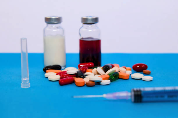 An array of medicine vials, pill blister packs, and a syringe, hinting at healthcare treatments and pharmaceuticals.