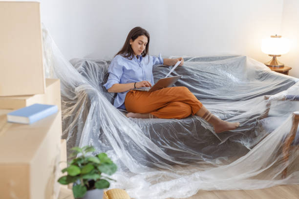 istock Young woman using laptop in new home and holding documents 2162498891