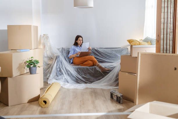 istock Young woman using laptop in new home and holding documents 2162498894