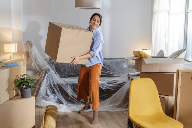 istock Young woman carrying box while moving house 2162498995