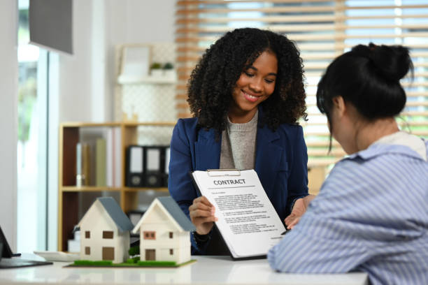 istock Friendly female real estate agent pointing at contract document to client put a signature. Real estate and property insurance concepts 2162503462