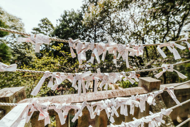 A close-up view of traditional Japanese paper lanterns featuring kanji characters, floral designs, and symbolic illustrations. The lanterns are neatly arranged on a metal rack, creating a cultural and artistic display in an outdoor setting.