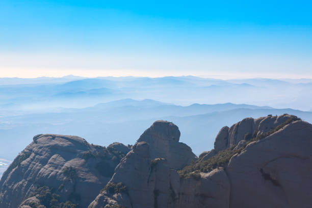 View from the peak of Montserrat, Catalonia, Spain. Mountain peak with haze overhead. Mountains are covered in fog and the sky is clear