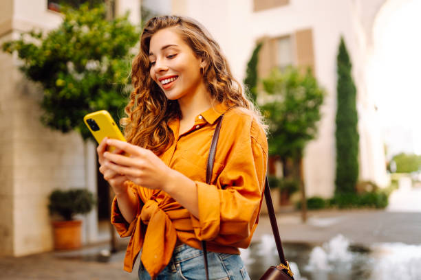 istock Young woman using a smart phone while walking on a sidewalk in the city. 2162510798