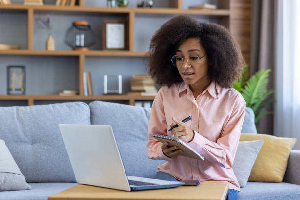 istock Woman working remotely from home on laptop while taking notes during online meeting 2162513366