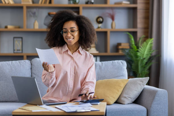 istock Woman working from home with documents and laptop, smiling at progress 2162513401