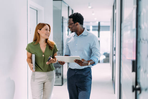 Business people in the office. Shot of two coworkers having a discussion in modern office. Businessman and businesswoman in meeting discussing important financial documents. Confident business people working together in the office. Corporate business persons discussing new project and sharing ideas in the workplace. black man white woman couple stock pictures, royalty-free photos & images