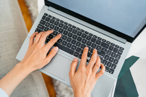 istock Young Woman Working On A Laptop While Sitting On The Sofa At Home 2162516463